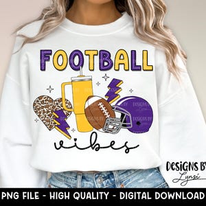 Pu&ograve; includere: Felpa bianca con un design viola e giallo che dice "FOOTBALL vibes". Il design include un pallone da calcio, un cuore, un fulmine e una tazza.