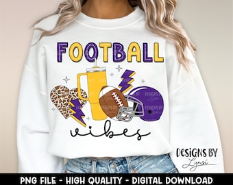 May include: White sweatshirt with a purple and yellow design that says "FOOTBALL vibes". The design includes a football, a heart, a lightning bolt, and a cup.