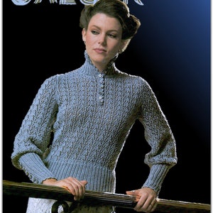 May include: A blue knitted sweater with a high neck and button closure. The sweater has a textured pattern and is worn by a person with dark hair.