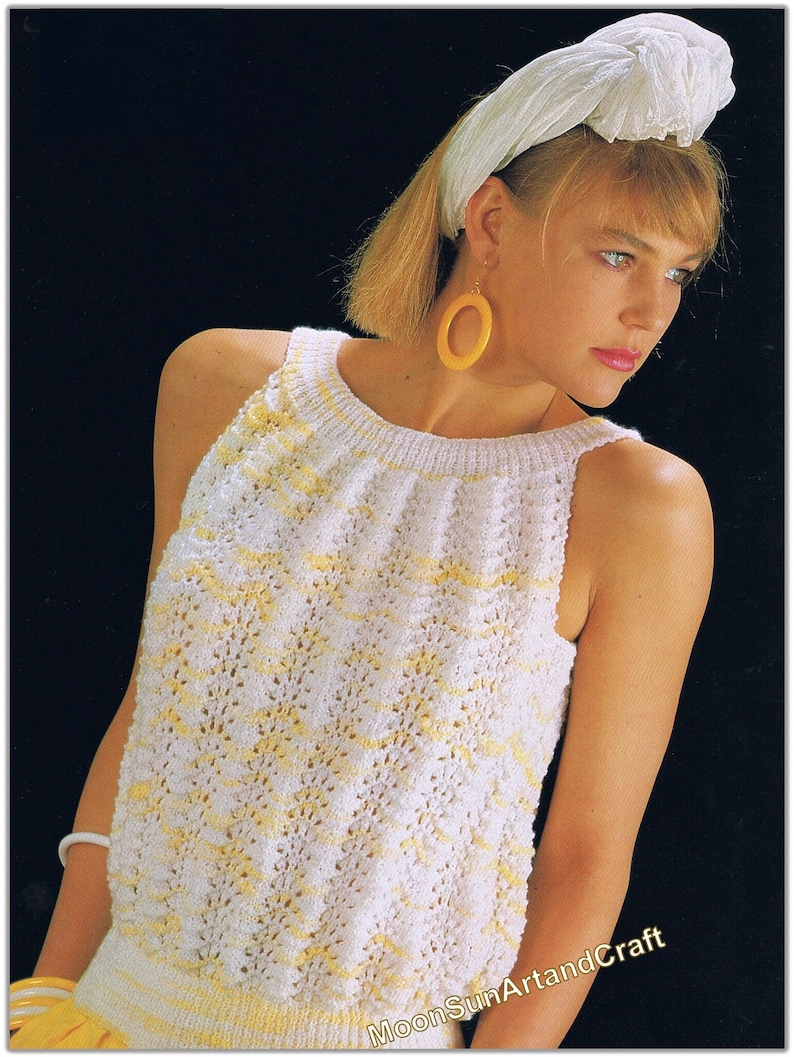 Puede incluir: Un top blanco de punto sin mangas con un patr&oacute;n amarillo y blanco. El top tiene un escote redondo y lo lleva una mujer con el pelo corto rubio y una diadema blanca. La mujer lleva grandes pendientes de aro amarillos.