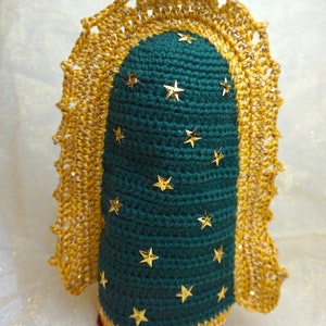 Puede incluir: Mu&ntilde;eca de crochet con cuerpo verde y ribete dorado. La mu&ntilde;eca est&aacute; decorada con estrellas doradas.