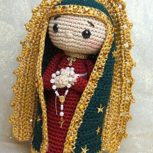 Puede incluir: Figurita de ganchillo de la Virgen Mar&iacute;a, vestida con una t&uacute;nica azul y dorada con una corona de oro y estrellas. Ella sostiene un rosario en sus manos.