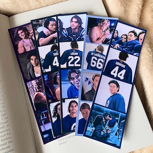 May include: Several photo bookmarks showing images of young men. The bookmarks are arranged on an open book. The bookmarks have a blue and white colour scheme. Text is visible on the pages of the book.