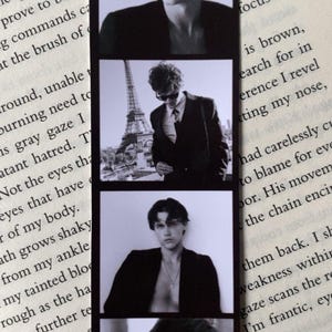 Puede incluir: Marcap&aacute;ginas en blanco y negro con cuatro im&aacute;genes estilo tira de pel&iacute;cula de una persona. Las im&aacute;genes muestran a la persona en varias poses, incluida una con la Torre Eiffel de fondo. El marcap&aacute;ginas es rectangular y tiene un borde negro.