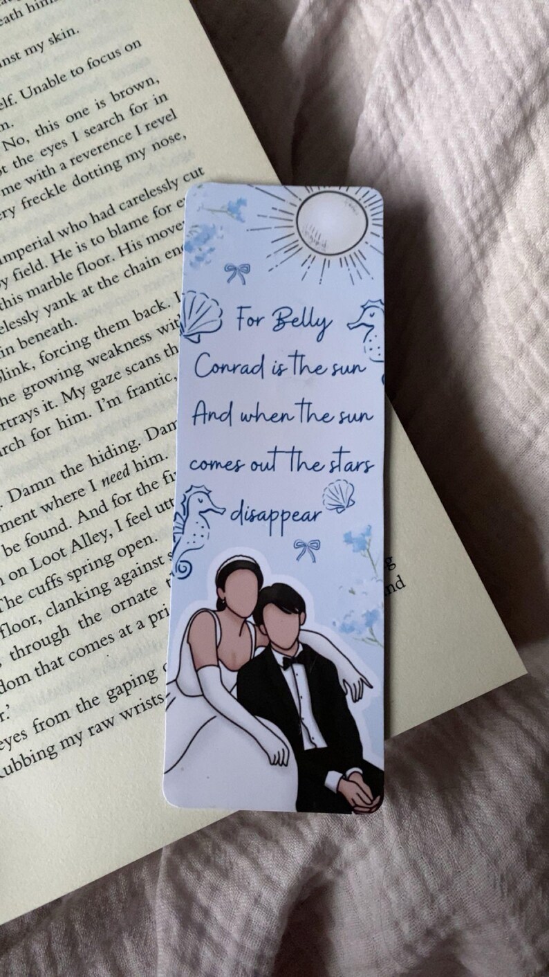 Puede incluir: Marcap&aacute;ginas rectangular con una ilustraci&oacute;n de pareja y texto. El texto dice: "Para Belly, Conrad es el sol, Y cuando sale el sol, las estrellas desaparecen". El marcap&aacute;ginas tiene un esquema de color azul claro y blanco.