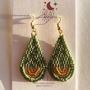 May include: A pair of green and gold teardrop-shaped beaded earrings. The earrings are made with small beads and have a gold-colored wire hook.