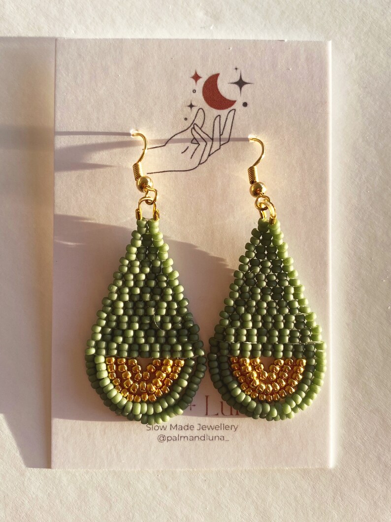May include: A pair of green and gold teardrop-shaped beaded earrings. The earrings are made with small beads and have a gold-colored wire hook.