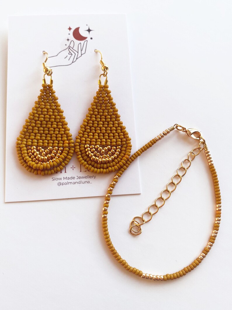 May include: A set of mustard yellow beaded earrings and a matching bracelet. The earrings are teardrop shaped and have a gold accent. The bracelet is a simple chain with a gold clasp.