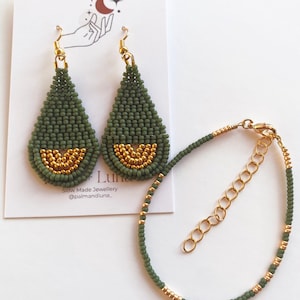 May include: A set of green and gold beaded earrings and a matching bracelet. The earrings are teardrop shaped and the bracelet is delicate. The earrings and bracelet are made with small, round beads.