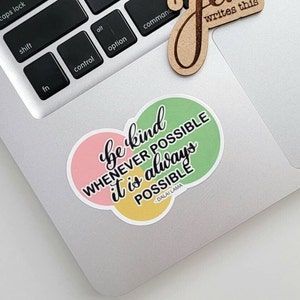 May include: A sticker with a quote from the Dalai Lama: "Be kind whenever possible. It is always possible." The quote is written in black text on a background of three overlapping circles in pink, yellow, and green.