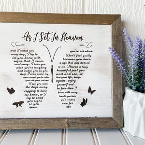May include: A framed wooden sign with the text "As I Sit In Heaven" and a poem shaped like a butterfly. The sign is in a rustic style with a white background and a brown frame. Decorative butterflies are also included.