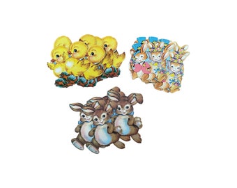 May include: A set of three Easter-themed paper cutouts featuring yellow chicks, brown bunnies, and blue bunnies. The chicks are arranged in a cluster, while the bunnies are in a line. All the cutouts have painted details and are ready to be used for crafts or decorations.