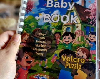 May include: A colorful baby book with the title "Baby BOOK" and illustrations of children playing. The book features 11 pages, 6 puzzles, 5 interactive Velcro games, and 4 point learning drawing activities. The cover also says "Velcro Puzzle".