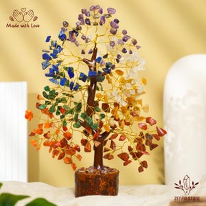 K&ouml;nnte beinhalten: Ein Kristallbaum mit sieben verschiedenen farbigen Steinen, darunter Amethyst, Lapislazuli, klarer Quarz, Citrin, gr&uuml;ner Aventurin, Karneol und roter Jaspis. Der Baum ist aus Draht gefertigt und hat einen braunen Holzsockel. "Made with Love" steht auf dem Bild.