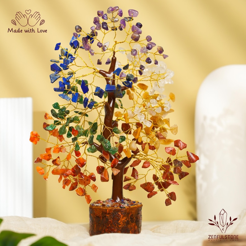 K&ouml;nnte beinhalten: Ein Kristallbaum mit sieben verschiedenen farbigen Steinen, darunter Amethyst, Lapislazuli, klarer Quarz, Citrin, gr&uuml;ner Aventurin, Karneol und roter Jaspis. Der Baum ist aus Draht gefertigt und hat einen braunen Holzsockel. "Made with Love" steht auf dem Bild.