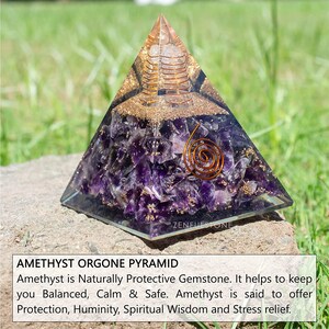 May include: Amethyst orgone pyramid with a copper coil inside. The pyramid is made of clear resin with amethyst crystals embedded in it. The pyramid is sitting on a rock with green grass in the background. ZENFULSTONE is printed on the base of the pyramid.