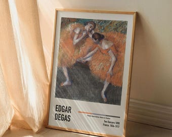 May include: A framed print of a painting by Edgar Degas titled "Two Dancers" from 1898. The painting depicts two dancers in orange tutus, one with her arm around the other's waist, against a dark background.