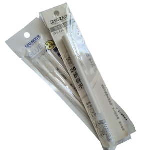 May include: A pack of white glue sticks with the brand name "SHANDS" and the text "GLUE" printed on the packaging. The glue sticks are labelled "20 秒快干" which translates to "20 seconds fast drying".