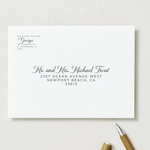May include: A white envelope with black calligraphy. The text reads "Mr. and Mrs. Michael Trout" and an address. The upper left corner has the text "The Future Mr. & Mrs. George" and an address. A gold pen is on the surface.