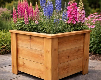 Könnte beinhalten: Ein hölzerner Pflanzkasten gefüllt mit leuchtenden Blumen. Die Box besteht aus hellem Holz und hat eine rechteckige Form. Die Blumen umfassen rosa, blaue und violette Blüten, die eine farbenfrohe Darstellung schaffen. Der Pflanzkasten steht auf einer Steinoberfläche, mit Grün im Hintergrund.