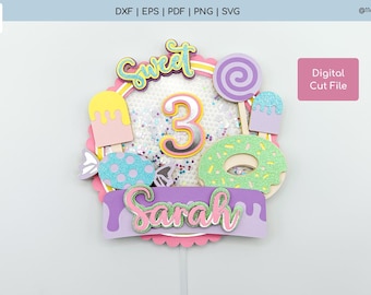 May include: A multi-layered cake topper featuring the text Sweet and Sarah, the number 3, and various candy-themed elements including a lollipop, donut, and popsicle. The design incorporates pastel colors, glitter accents, and a shaker-style center.