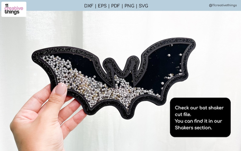 K&ouml;nnte beinhalten: Ein schwarzer, fledermausf&ouml;rmiger Shaker mit Glitzerrand. Der Shaker ist mit silbernen und goldenen Streuseln gef&uuml;llt. Der Text "Check our bat shaker cut file. You can find it in our Shakers section." steht auf einem schwarzen Rechteck.