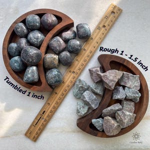 Puede incluir: Dos bandejas de madera exhiben piedras preciosas pulidas y en bruto. Las piedras pulidas miden aproximadamente 2,5 cm, mientras que las piedras en bruto varían de 2,5 a 3,8 cm. Una regla de madera se coloca junto a las piedras. El texto "Tumbled 1 inch" y "Rough 1 - 1.5 inch" son visibles.