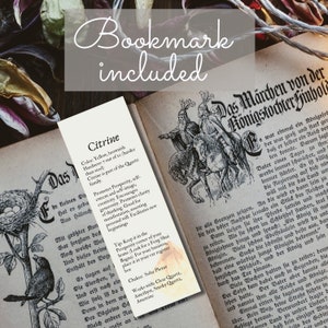 May include: A bookmark with a yellow and brown citrine crystal illustration. The bookmark features text describing the crystal's properties, including its color, hardness, and metaphysical benefits. The text also includes a tip on how to use the crystal for prosperity and a list of crystals that work well with citrine.