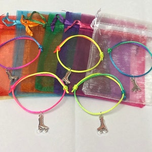 May include: A selection of friendship bracelets featuring roller skate charms. The bracelets are made from brightly coloured cord and presented in small, sheer organza bags in shades like pink, yellow, green, and blue.