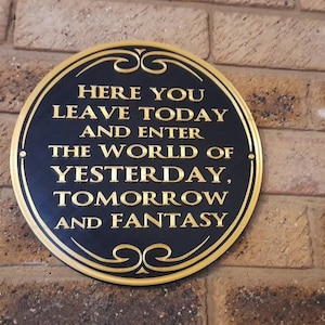 May include: A gold plaque with black lettering on a brick wall. The plaque reads "Here you leave today and enter the world of yesterday, tomorrow and fantasy."