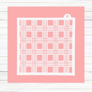 May include: A white stencil with a checkered pattern on a pink background. The stencil is designed for crafting and decorating.