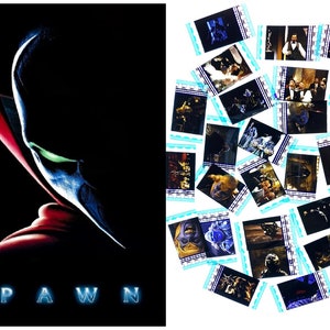 May include: A movie poster for the film "Spawn" featuring a close-up of the main character's face. The character is a dark, shadowy figure with glowing green eyes and a red and blue cape. The title of the film is written in large, white letters at the bottom of the poster.