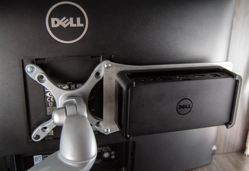 May include: A Dell monitor with a Dell computer mounted to the back. The monitor is attached to a silver arm.
