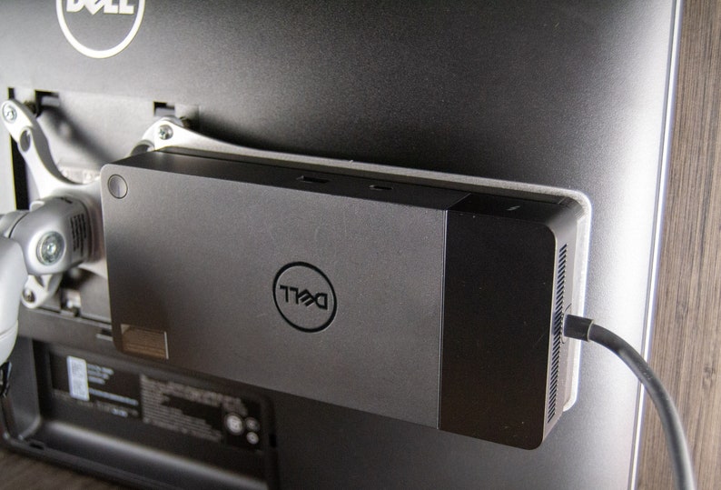 May include: A black Dell monitor stand with a Dell logo and multiple ports. The stand is attached to the back of a monitor.