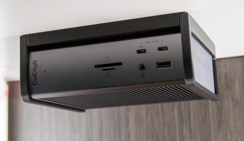 Op de afbeelding: Een zwarte CalDigit docking station met meerdere poorten, waaronder USB, Thunderbolt en audio. Het apparaat heeft een strak, modern ontwerp met een geribbelde onderkant voor ventilatie. Het CalDigit-logo is zichtbaar.