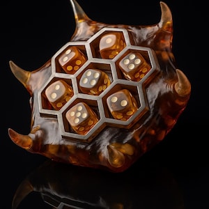 May include: A unique dice holder with a honeycomb design, holding six transparent dice. The holder is amber-colored with silver accents, and has horn-like protrusions. The dice have white pips.
