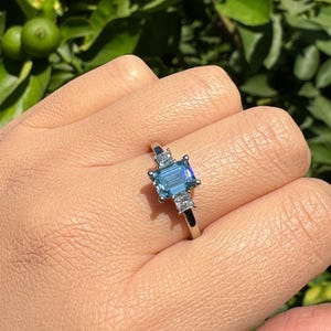 1.4 CTW. VVS2 Emerald Cut Fancy Intense Blue Lab Grown Diamond Three Stone 14K Gold Engagement Ring with two Princess Cut Square Diamonds