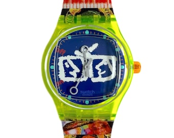 Könnte beinhalten: Eine leuchtend grüne Swatch-Uhr mit blauem Zifferblatt und weißen Graffiti-Lettern. Die Uhr hat ein buntes Armband mit einem Klaviertasten-Design.