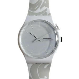 Puede incluir: Reloj de pulsera blanco con una correa de patrón gris. La esfera del reloj es blanca con manecillas plateadas y un logotipo 'Swatch Swiss' plateado.