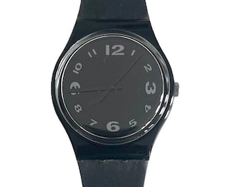 Peut inclure: Une montre-bracelet noire avec un bracelet en caoutchouc noir et un cadran noir avec des chiffres blancs. La montre a un design simple et est un style classique.