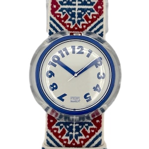 Könnte beinhalten: Eine Swatch Pop-Uhr mit weißem Zifferblatt, blauen Ziffern und Zeigern. Die Uhr hat ein transparentes Kunststoffgehäuse und ein Armband mit einem Muster in Rot, Weiß und Blau. Auf dem Zifferblatt steht "POP Swatch".
