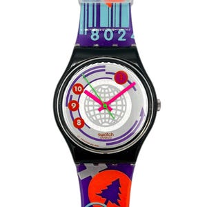 Op de afbeelding: Een witte keramische mok met een zwart handvat en de tekst "But first, coffee" in een zwarte, handgeschreven lettertype. De mok staat op een wit oppervlak.