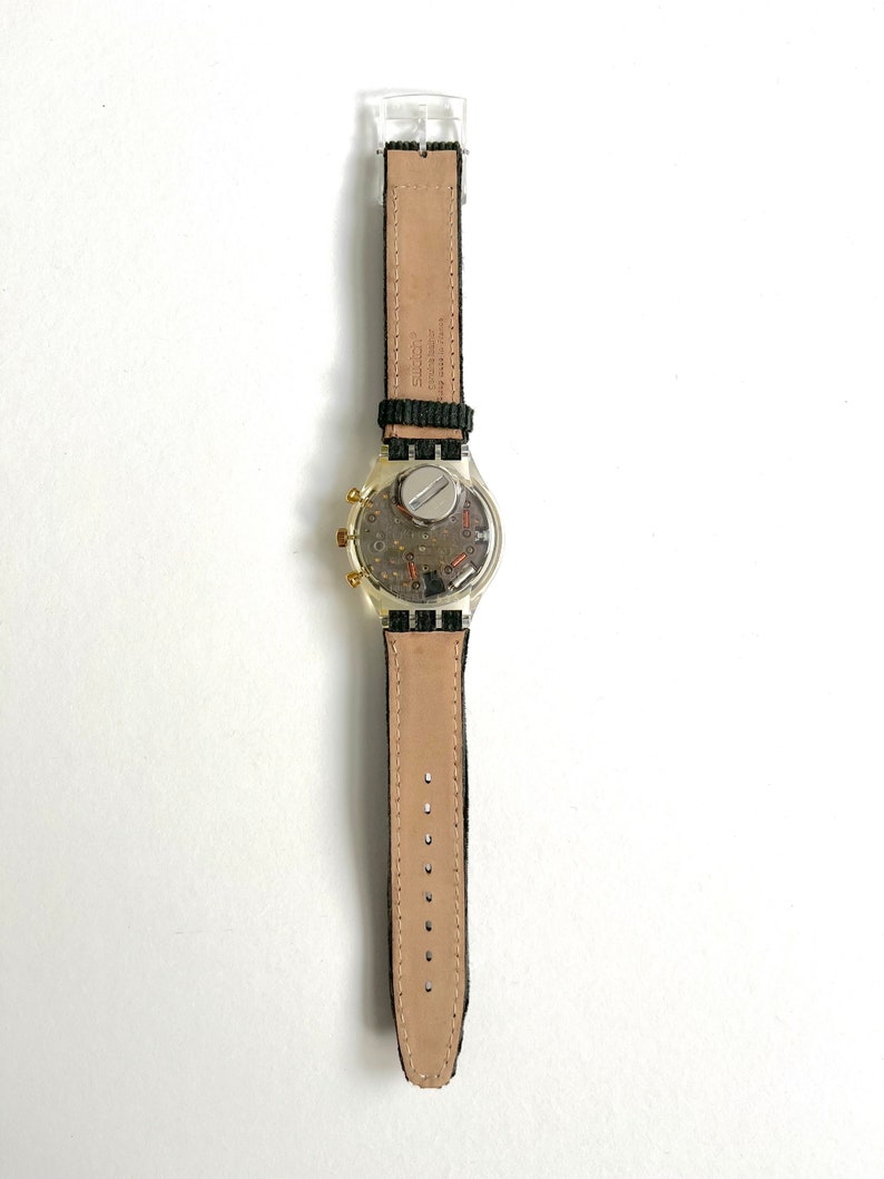 May include: A silver and gold wristwatch with a black leather band. The watch face is visible and has a chronograph function.