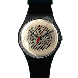May include: Black Swatch watch with a beige face featuring black lines and text. The watch has a red second hand and displays "SAT 6". The watch band is black.
