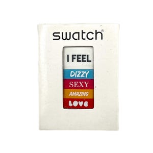 Op de afbeelding: Een witte Swatch-doos met een rechthoekig venster met kleurrijke tekst. De tekst luidt "I FEEL DIZZY SEXY AMAZING LOVE" in een gestapeld formaat. Het Swatch-logo staat bovenaan de doos.