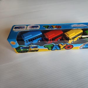 May include: A set of four colorful toy buses with the words "Tayo The Little Bus" and "Pull Back Toys" on the box. The buses are blue, red, yellow, and green.