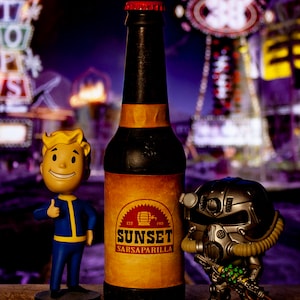 May include: A brown glass bottle of Sunset Sarsaparilla, a fictional soda from the Fallout video game series, with a red cap and a yellow label. The bottle is sitting on a table with a Vault-Tec logo and a Fallout Power Armour figure.