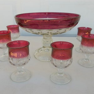 Puede incluir: Un juego de ponchera de vidrio vintage con un cuenco grande y seis vasos a juego. El juego presenta un borde rojo vibrante y un diseño de vidrio transparente y texturizado. Ideal para servir bebidas.