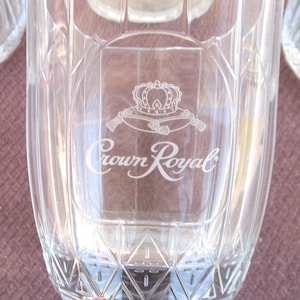 Puede incluir: Un vaso de vidrio transparente con un patrón de diamante. El vaso tiene un diseño grabado de una corona y las palabras "Crown Royal".