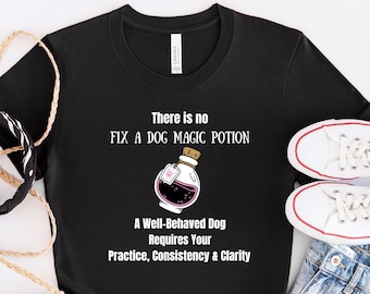 May include: Black t-shirt with white text that reads "There is no fix a dog magic potion. A well-behaved dog requires your practice, consistency & clarity."  The text is accompanied by a cartoon image of a potion bottle with a pink label.